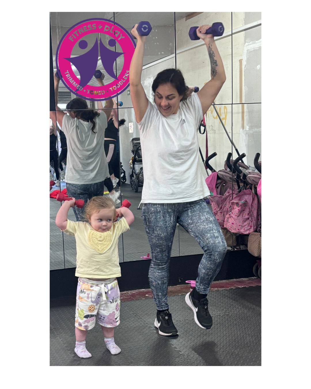 Mam lifting dumbbells overhead while her toddler copies alongside her at a Fitness and Play class